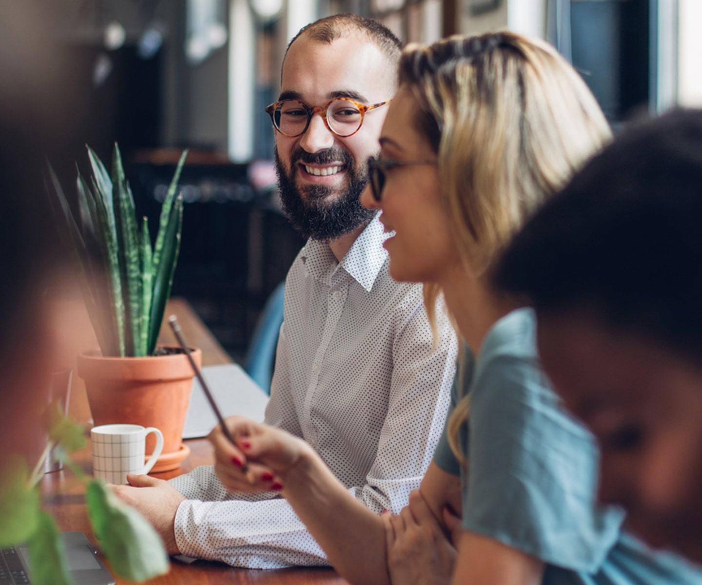A man smiling in a group of coworkers around a table