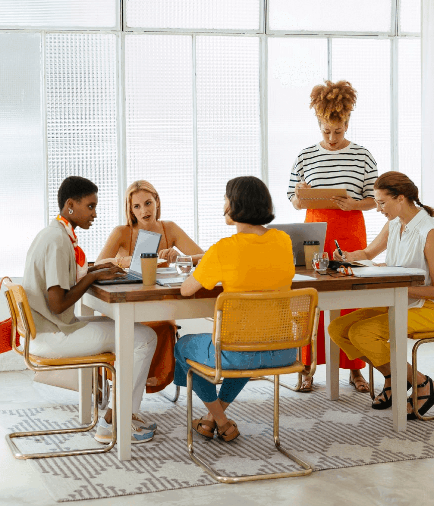 Group of women in brightly colored office collaborating