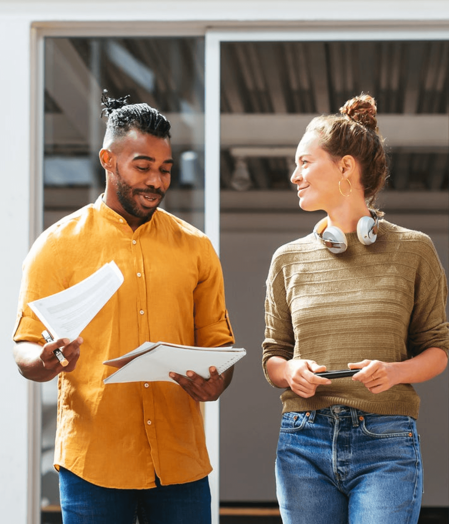 Two coworkers in warm toned shirts conversing while walking